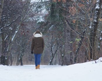 Rear view of woman walking on snow covered land