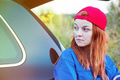 Thoughtful mechanic looking away against breakdown car