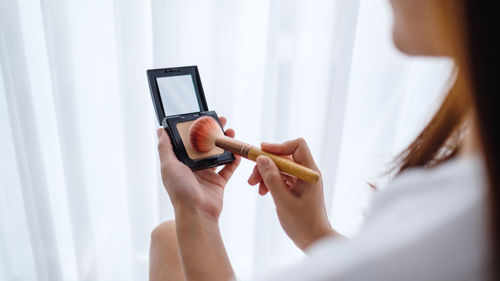 Midsection of woman using make-up