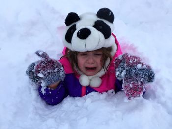 High angle view of crying girl buried in snow during winter