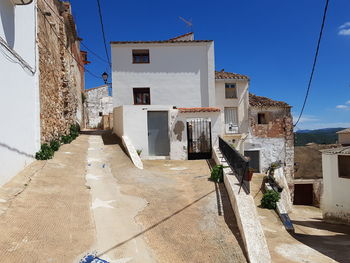 Alley amidst buildings in town against blue sky