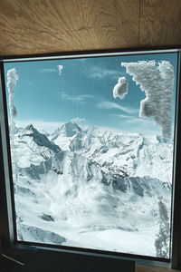 Scenic view of snowcapped mountains seen through glass window