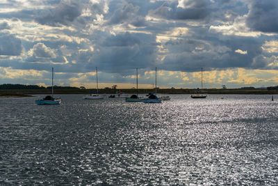 Sailboats sailing on sea against sky during sunset
