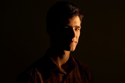 Close-up portrait of young man against black background