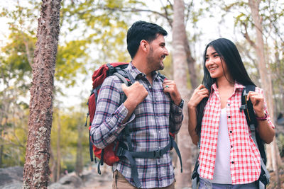 Young couple standing against trees