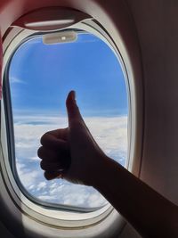 Cropped hand of person gesturing by airplane window