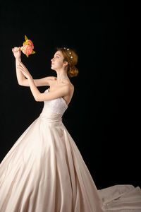 Woman holding flowers against black background