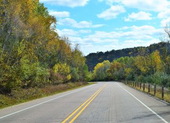 Road by trees against sky