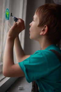 Side view of boy playing with camera