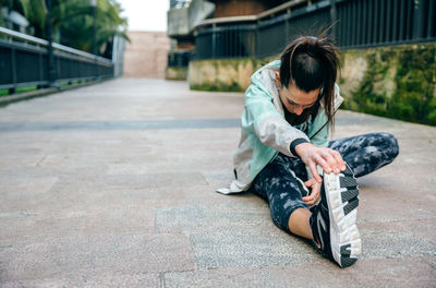 Side view of young woman sitting on road