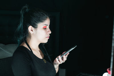 Beautiful latin woman with green hair, looking at her cell phone, with a confused expression 