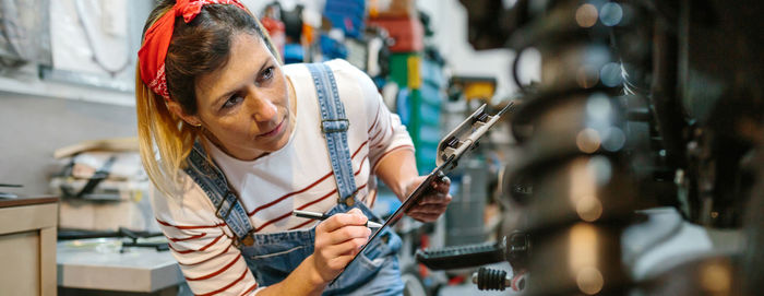 Mechanic woman filling out motorcycle documentation on garage