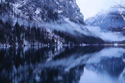 Scenic view of lake by snowcapped mountains against sky