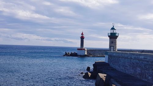 Lighthouse by sea against sky