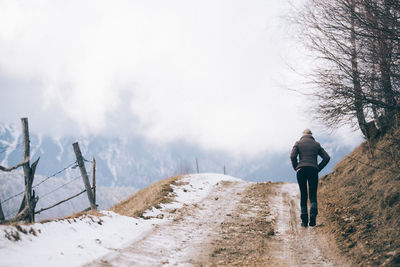Rear view of woman walking on road during winter