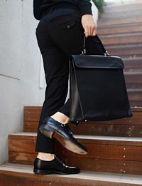 Low section of businessman carrying bag while climbing steps in office