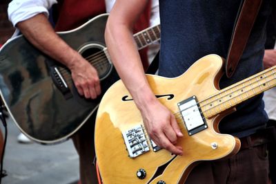 Midsection of street musicians playing guitars