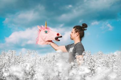 Man holding unicorn mask in white field