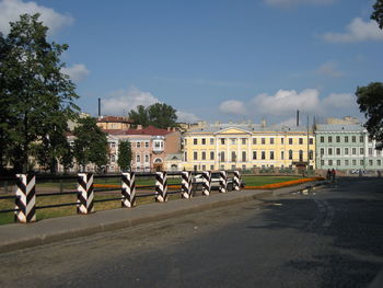 Road by buildings in city against sky