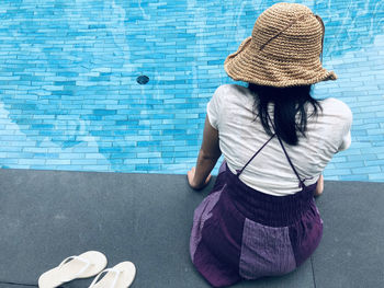 Rear view of woman sitting by swimming pool