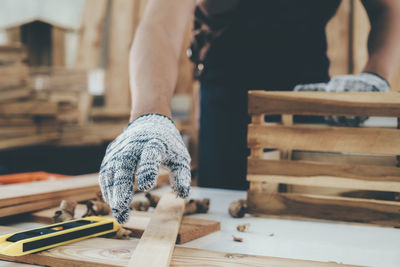 Midsection of carpenter holding plank on table