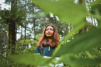 Woman standing against trees in forest