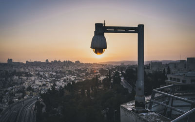 Lamp on terrace against cityscape during sunset