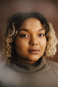 Portrait of woman wearing turtleneck against brown background
