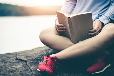 Low section of woman sitting on book