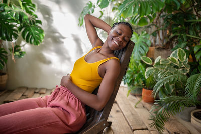 Portrait of young woman sitting against plants