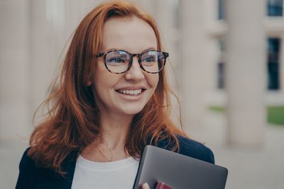 Portrait of smiling young woman using smart phone outdoors