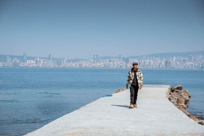 Rear view of woman standing on beach against clear sky