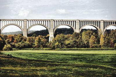 Arch bridge on landscape against sky