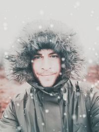 Portrait of young man wearing warm clothing during snowfall