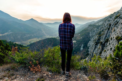 Rear view of woman standing on mountain against sky