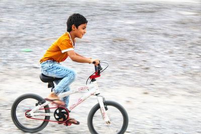 Side view of boy riding bicycle on road