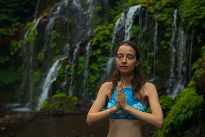 Woman standing against waterfall in forest