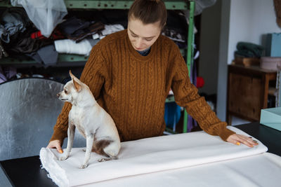 Woman holding textile with dog at table in workshop