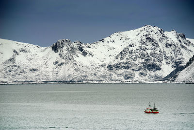 Sailboat on snowcapped mountain against sky