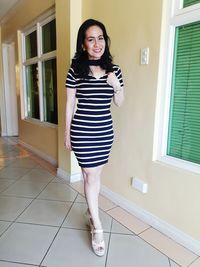 Full length portrait of young woman walking on corridor