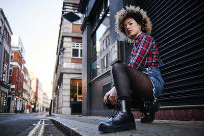 Young woman sitting on street in city