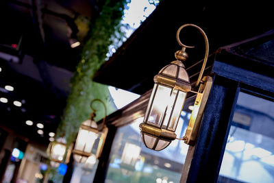 Low angle view of illuminated light bulb hanging from ceiling