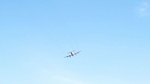 Low angle view of airplane against clear blue sky