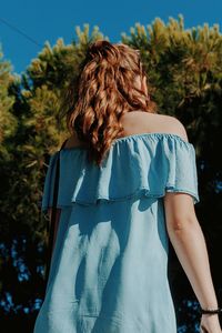 Rear view of young woman standing against sky