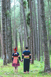 Rear view of people walking in forest