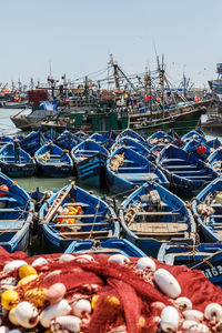 Fishing boats moored at harbor against clear sky