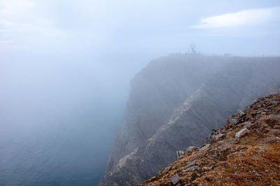 Scenic view of sea by mountain against sky