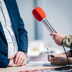 Journalists holding microphone, interviewing speaker.