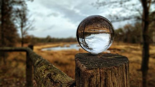 Close-up of crystal ball on old wooden post