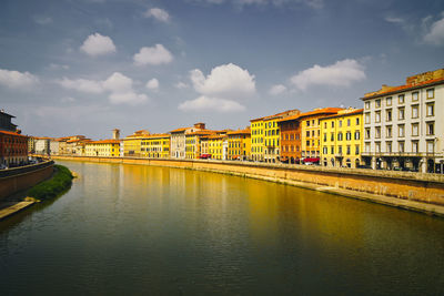 Bridge over river by buildings in city against sky